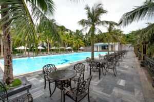 A serene poolside area at a tropical resort, featuring palm trees and elegant seating.